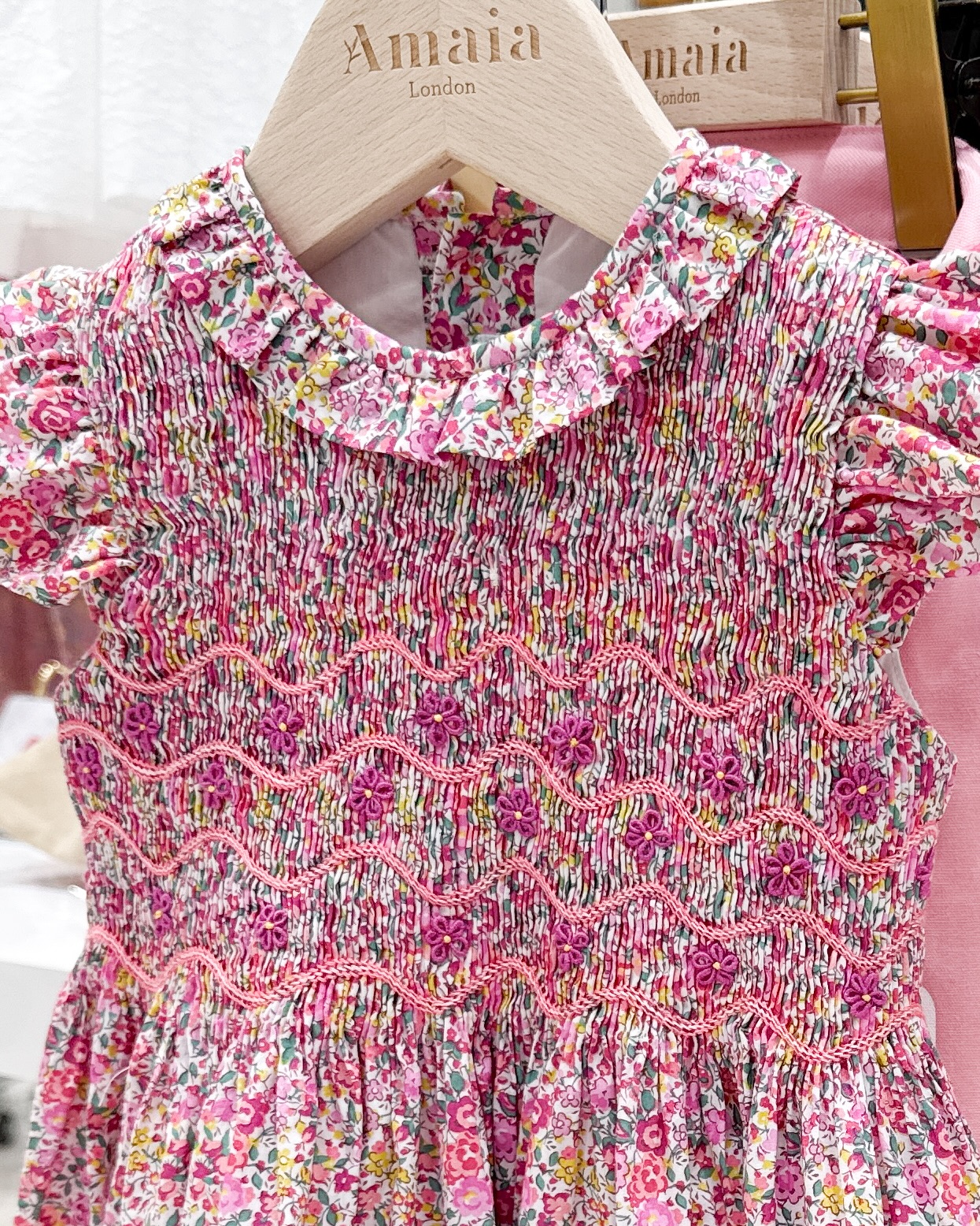 『Falbala dress』の美しい手刺繍🪡🧵胸元に施されたスモッキング刺繍は、職人が一針ずつ丁寧に仕上げた特別なもの。リバティプリントに、フューシャピンクのお花が優雅に浮かび上がりピンク模様が華やかさを添えますフリル襟と贅沢に生地を使用した細やかなギャザーがふわりと広がり、可愛らしくもエレガント特別な日の装いに。そして、出産祝いにもぴったりの一着です♡【Amaia Kids SS25 POP UP】～4月15日（火）まで、伊勢丹新宿店 本館6階 リ・スタイルキッズにて開催中#アマイアキッズ #amaiakids #amaiajapan #出産祝い #ベビーギフト #英国子供服 #イギリスブランド #女の子ワンピース #リバティプリント #手刺繍 #スプリングコーデ #伊勢丹新宿店 #isetan@amaia_japan⁡▼オンラインショップhttps://amaia.jp